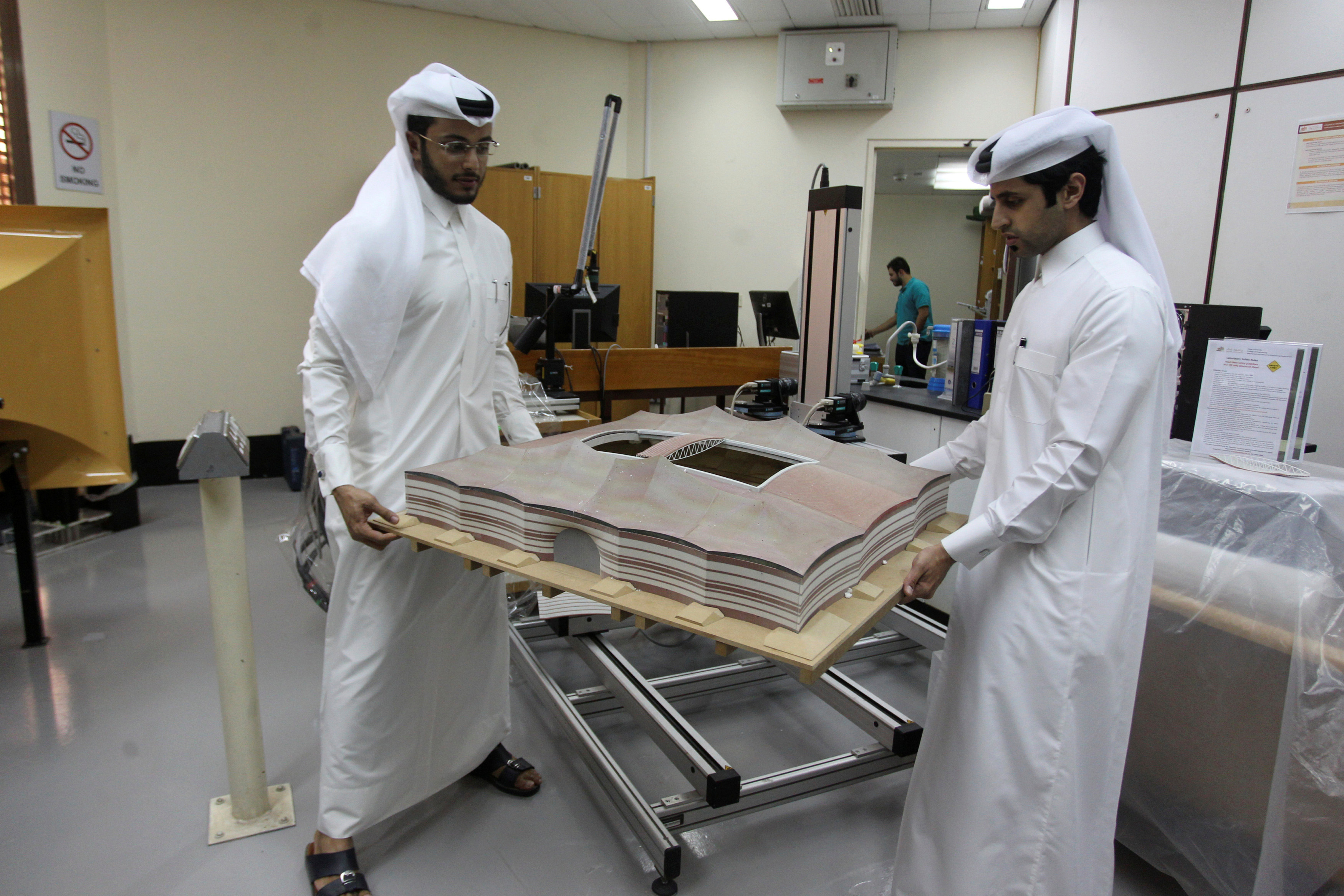 Mechanical engineers Abdullah Mojeb Aldar (L) and Fahad al-Musalam move a 3-D-printed model of Qatar's Al Bayt stadium, which will host a World Cup semi-final in 2022, at a laboratory at Qatar University in Doha, June 16, 2016. (Reuters)