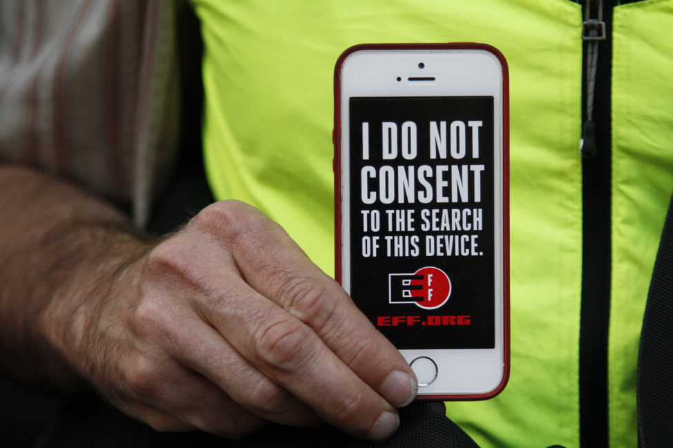 A man holds up his iPhone during a rally in support of data privacy outside the Apple store, Feb. 23, 2016, in San Francisco. 