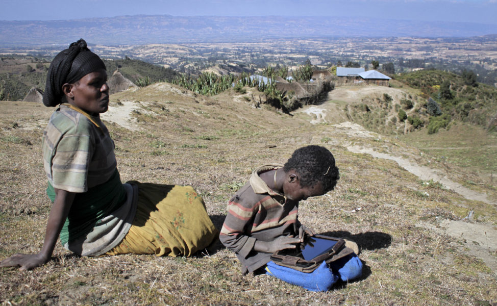 FILE - Abelbech Wagari sits near her son, Kelbesa Negusse as he plays with a tablet computer given to him by the One Laptop Per Child project in the village of Wenchi, Ethiopia. (AP)