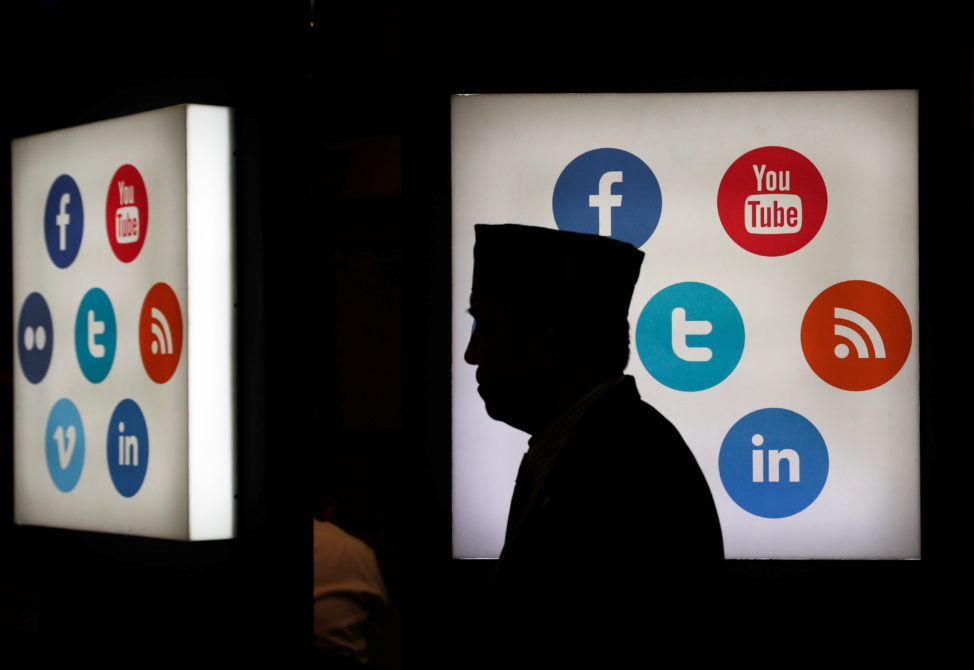 FILE - A man walks in front of social media logos in Jakarta, Indonesia. (Reuters)