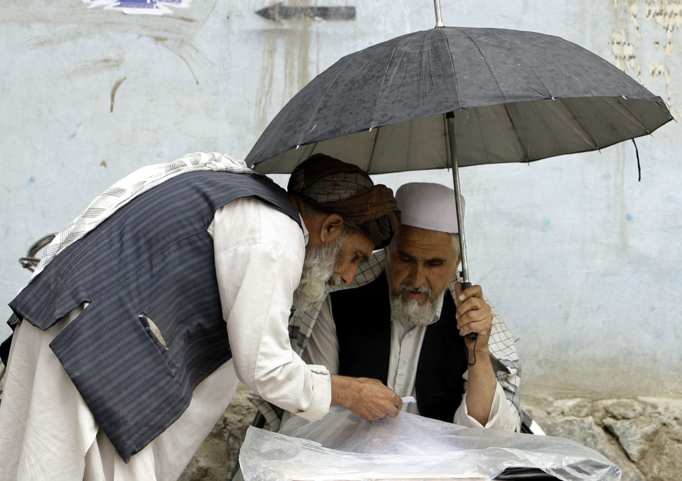 FILE - An Afghan letter writer (R) writes for his customer in Kabul May 17, 2010. (Reuters)