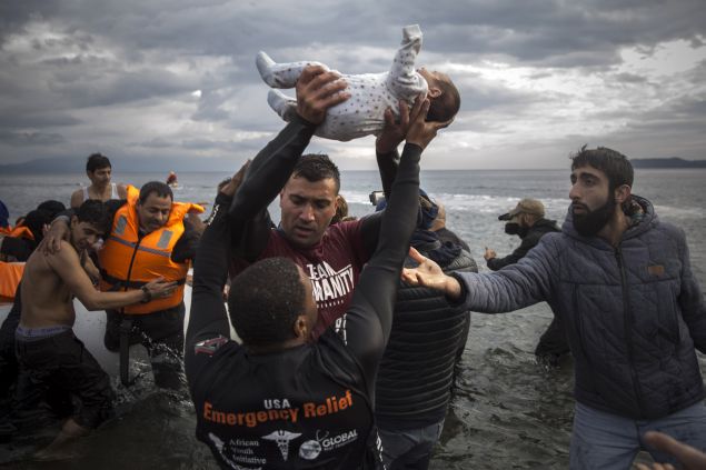 A volunteer holds up a baby as others help migrants and refugees to disembark from a dinghy after their arrival from the Turkish coast to the Greek island of Lesbos, Wednesday, Nov. 25, 2015. About 5,000 migrants reaching Europe each day over the so-called Balkan migrant route. The refugee crisis is stoking tensions among the countries on the so-called Balkan migrant corridor — Greece, Macedonia, Serbia, Croatia and Slovenia. (AP Photo/Santi Palacios)