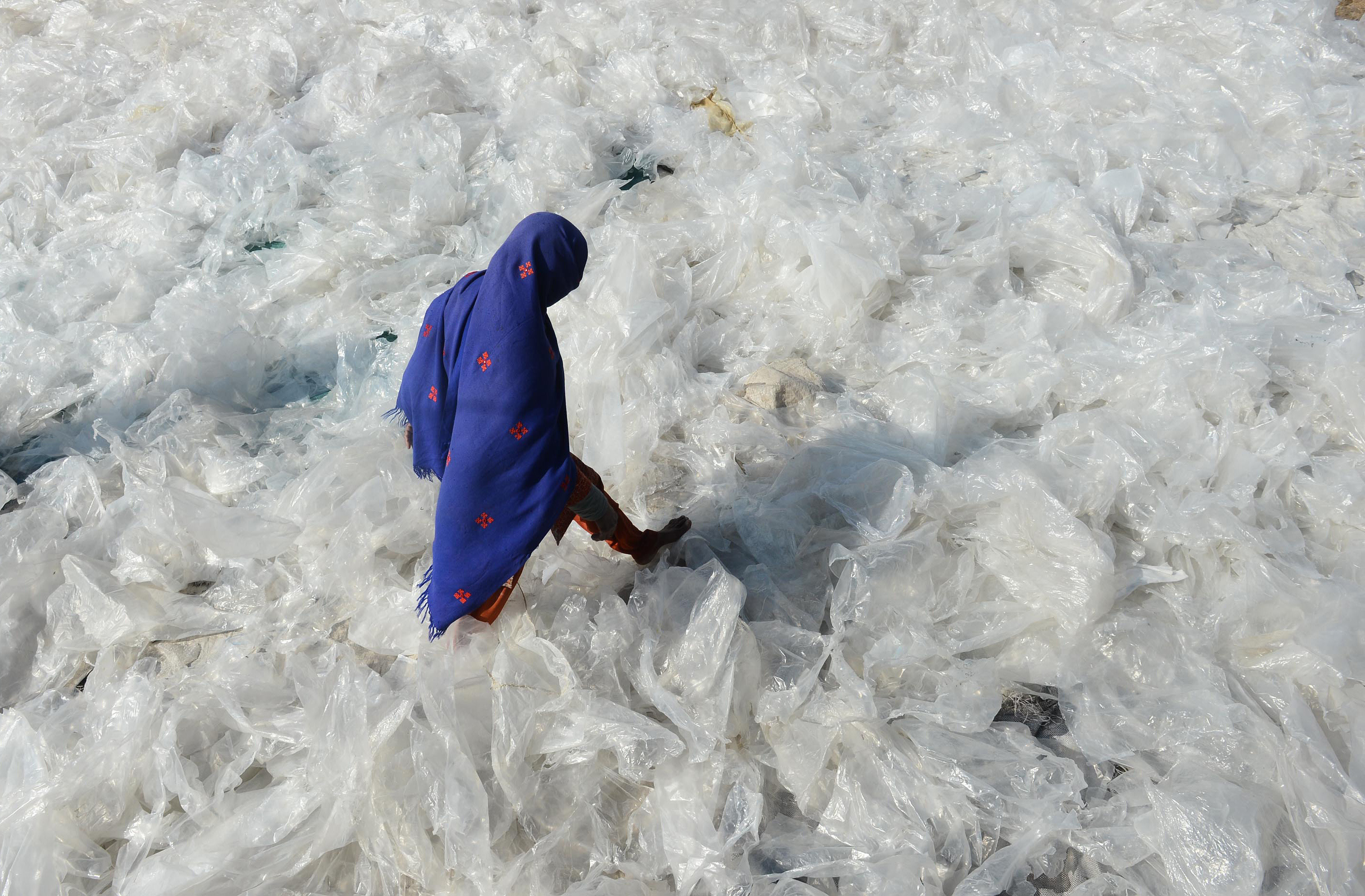 Pakistan'da bir kadın plastik torbaların üzerinde yürüyor