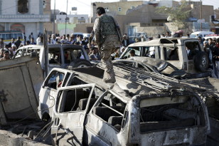 A Houthi fighter walks on a vehicle damaged by an air strike at a residential area near Yemen's Sanaa Airport March 26, 2015.