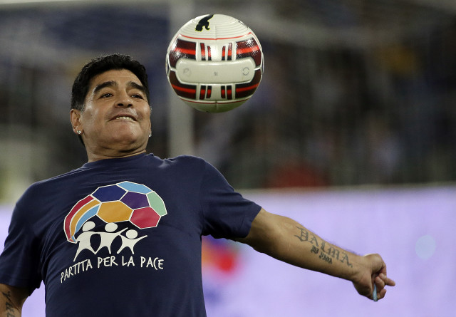 Argentine soccer legend Diego Armando Maradona watches the ball as he warms up prior to an  inter-religious match at Rome's Olympic Stadium,  Sept. 1, 2014. (AP Photo/Gregorio Borgia)