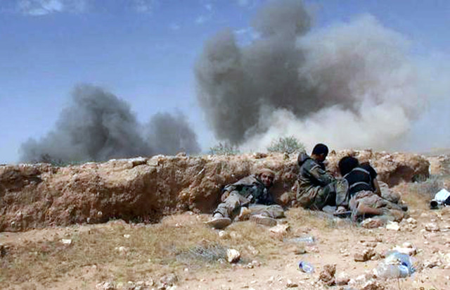 Islamic State fighters take cover during a battle against Syrian government forces on a road between Homs and Palmyra, Syria. (The website of Islamic State militants via AP)