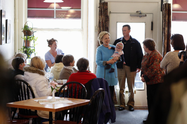 Caron Morse watches at left, watches as Democratic presidential candidate Hillary Clinton carries her granddaughter during a campaign stop at Kristin's Bakery on April 20, 2015, in Keene, N.H. (AP Photo/Jim Cole)