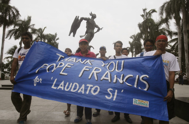 Environmental activists carry a banner as they march towards a Roman Catholic church coinciding with Pope Francis' encyclical on climate change on June 18, 2015 in Manila. (AP)