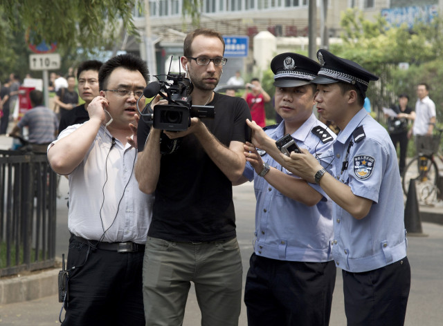 Chinese police officers try to block a journalist from filming the court house in Beijing, China, June 20, 2012. (AP Photo/Andy Wong)