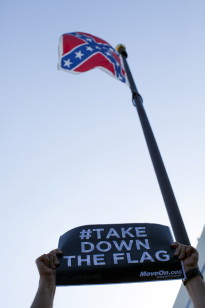 A protester holds a sign asking for the removal of the confederate battle flag that flies at the South Carolina State House in Columbia, SC on June 20, 2015.(Reuters)  