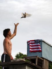 A man releases a pigeon next to a U.S. national flag in Havana on July 1, 2015. (AFP/Getty Images)