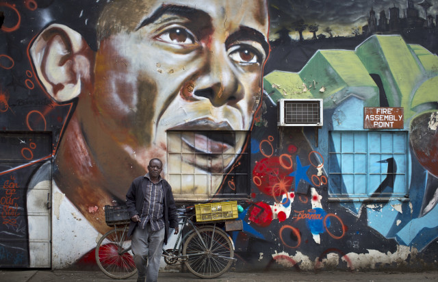 A man leans his bicycle against a mural of President Barack Obama, created by \Kenyan graffiti artist Bankslave, at the GoDown Arts Center in Nairobi, Kenya on July 22, 2015. (AP)