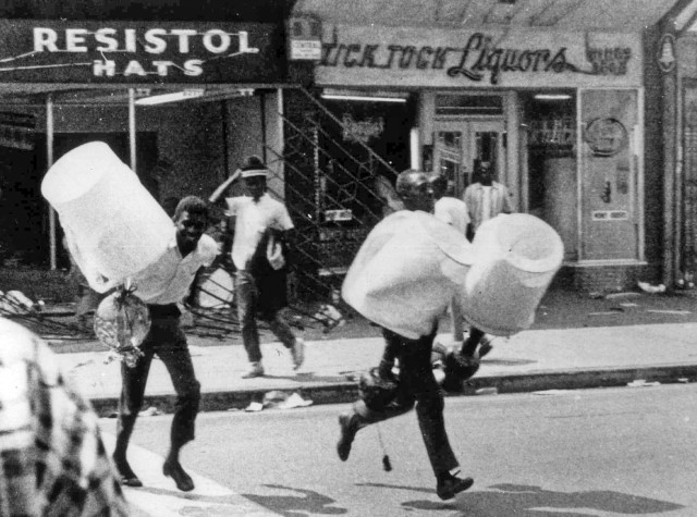 In this Aug. 13, 1965 file photo, men carry items from a looted store during the rioting that enveloped the Watts district of Los Angeles.