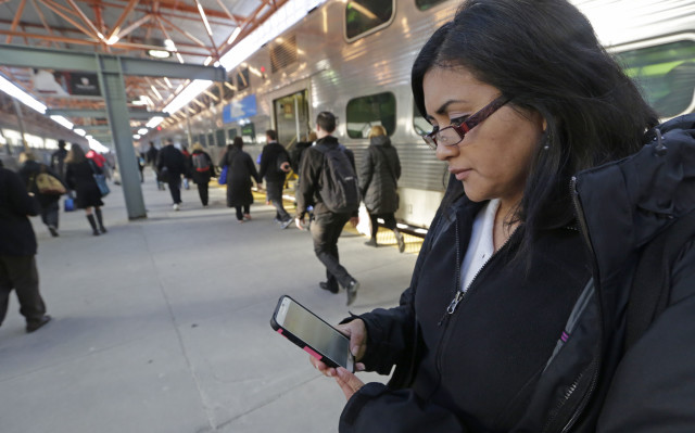 Marilu Rodriguez, a young adult or "millennial," checks a news website on her smartphone before boarding a train in Chicago on March 13, 2015. (AP)