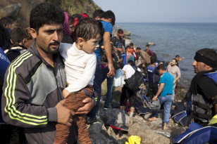 A Syrian refugee holds a boy moments after arriving on a dinghy on the Greek island of Lesbos on Sept. 3, 2015. (Reuters)