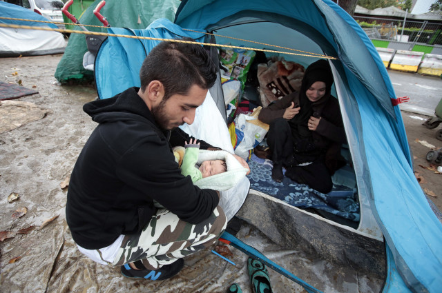 Ehab Ali Naser, a 23 year-old Syrian refugee, holds a 12 day-old baby at a makeshift camp on a street in northern Paris on Sept 16, 2015. (Reuters)