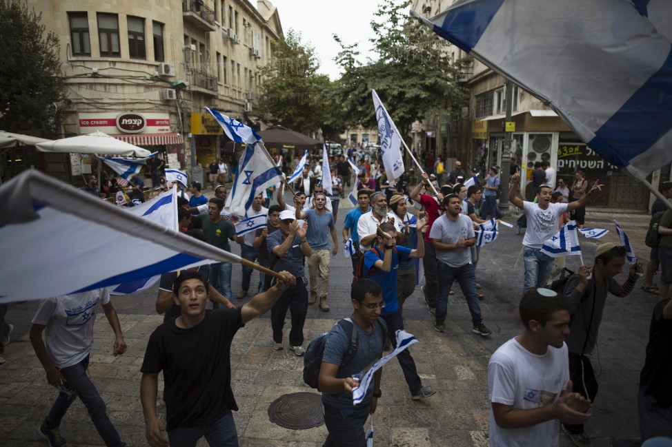 People sing and dance with Israeli national flags at a pedestrian street in downtown Jerusalem