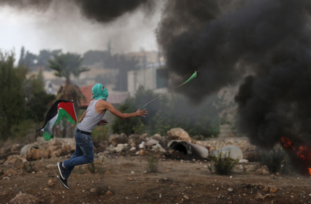 A Palestinian protester uses a sling to hurl stones towards Israeli troops during clashes near the Jewish settlement of Bet El, near the West Bank city of Ramallah on Oct. 18, 2015. (Reuters)