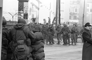 U.S. soldiers with automatic weapons stand behind sandbag barricade within few yards of East German soldiers assembled in front of workers adding to the wall at the Friedrich Strasse border crossing point in Berlin on Dec. 4, 1961. (AP)