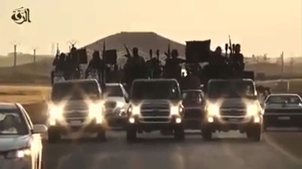 An image grab taken from a video released by Islamic State group's official Al-Raqqa site via YouTube on September 23, 2014, allegedly shows Islamic State (IS) group recruits riding in armed trucks in an unknown location.  