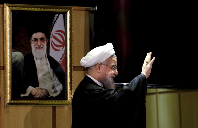 Iranian President Hassan Rouhani waves as he stands next to a portrait of Iran's Supreme Leader Ayatollah Ali Khamenei at interior ministry in Tehran December 21, 2015. (Reuters)