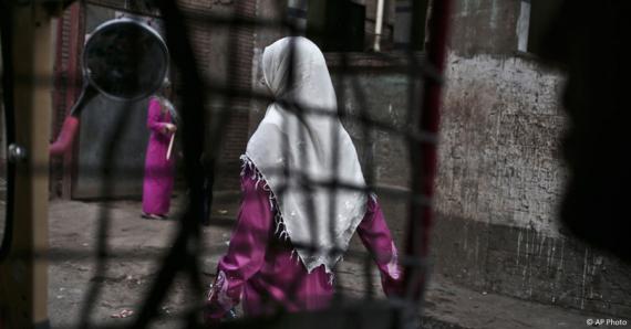 An Egyptian woman seen from a motorized rickshaw walks on a street, near the home of a 13-year old girl who died undergoing the procedure of female genital mutilation committed near Cairo, Egypt.(AP)