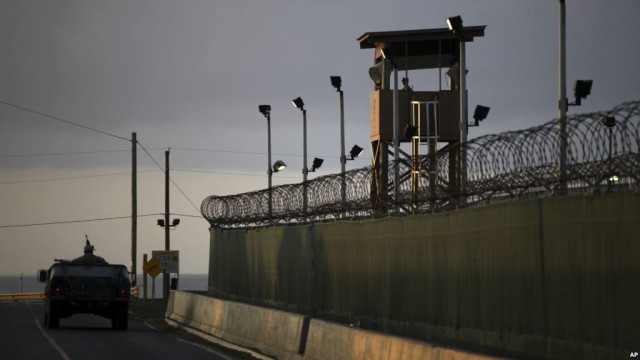 FILE - A U.S. soldier stands in the turret of a vehicle with a machine gun, left, as a guard looks out from a tower at the Guantanamo Bay prison in Cuba, March 30, 2010