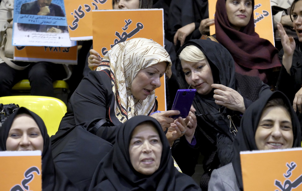 Women check the news on a mobile phone during a campaign gathering of candidates for the upcoming parliamentary elections mainly close to the reformist camp, in Tehran Feb. 23, 2016. REUTERS