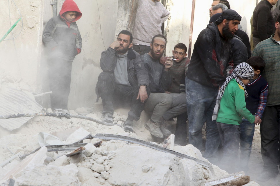 People sit on the rubble of a damaged building after airstrikes by pro-Syrian government forces in the rebel held city of Aleppo, Syria on Feb. 14, 2016. REUTERS