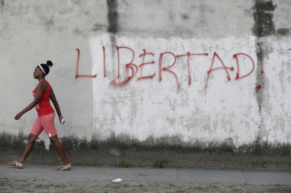 A young woman walks near graffiti that reads "Freedom" in Havana, Cuba on Feb. 21, 2016. (AP)