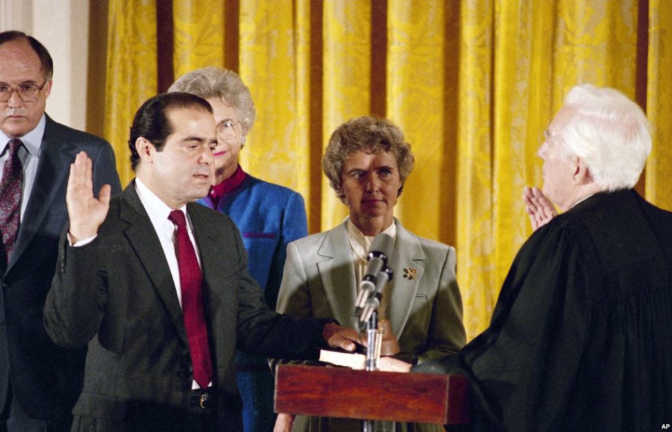 Retiring Chief Justice Warren Burger, right, administers an oath to Antonin Scalia, as Scalia's wife Maureen holds the bible in the East Room of White House, Sept. 26, 1986.