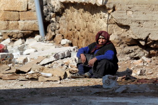 A woman rests near rubble on the ground in the town of Darat Izza in Aleppo, Syria on Feb. 28, 2016. (Reuters) 