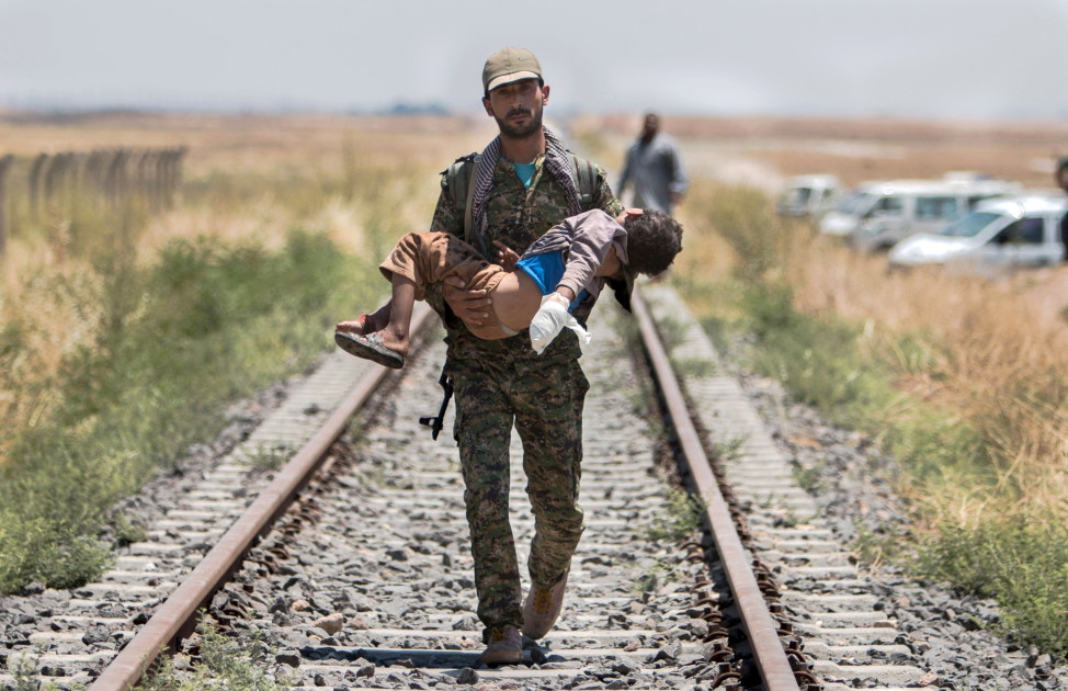 A Kurdish fighter carries a an injured boy in the border in Syrian Tel Abyad town of Raqqa, June 16, 2015. (Reuters)