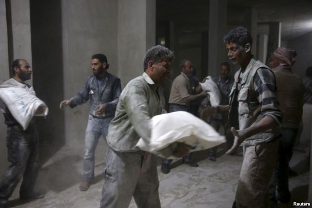 Men store bags of flour unloaded from a Red Crescent aid convoy in the rebel held besieged town of Jesreen, in the eastern Damascus suburb of Ghouta, Syria March 7, 2016 (Reuters) 