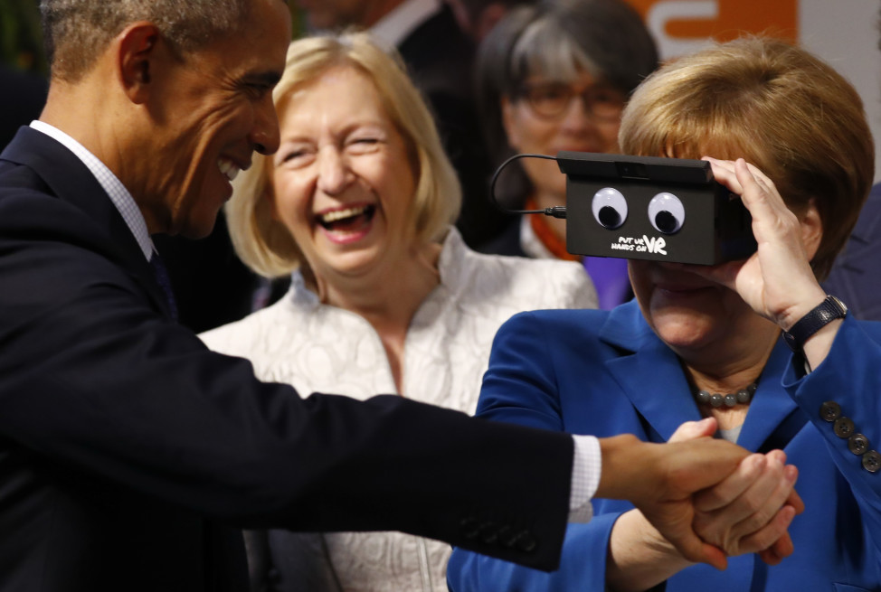 German Chancellor Angela Merkel and President Barack Obama react as they try the virtual reality device PMD in Hanover, Germany on April 25, 2016. (Reuters)