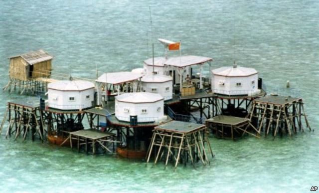 FILE - A Chinese flag and a satellite dish are prominently displayed in a structure built by China in one of the islands in the Spratly Islands.