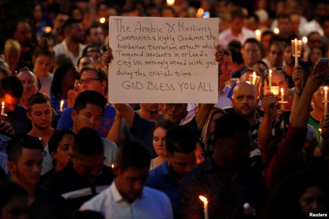 A man holds up a sign saying Arab Muslims condemn the attack as he takes part in a candlelight memorial service after a mass shooting at the Pulse gay nightclub in Orlando, Florida, June 13, 2016.