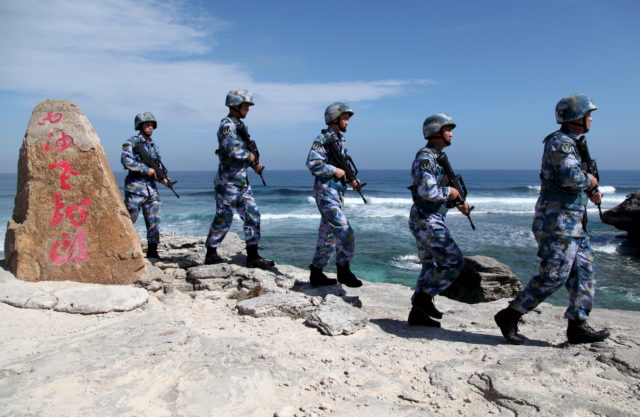 Soldiers of China's People's Liberation Army (PLA) Navy patrol at Woody Island, in the Paracel Archipelago, which is known in China as the Xisha Islands, January 29, 2016. The words on the rock read, "Xisha Old Dragon". Old Dragon is the local name of a pile of rocks near Woody Island. Picture taken January 29, 2016. (Reuters)