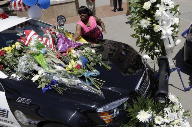 FILE - In this Friday, July 8, 2016 file photo, Cynthia Ware places flowers on a make-shift memorial at the Dallas police headquarters, in Dallas. Five police officers are dead and several injured following a shooting in downtown Dallas Thursday night. (AP)