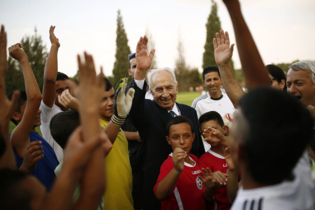 Former Israeli president Shimon Peres (C) is seen with Israeli and Palestinian children during an event opening a year of training of an Israeli-Palestinian soccer program launched by the Peres Center for Peace, in Kibbutz Dorot, outside the Gaza Strip, September 1, 2014. (Reuters) 