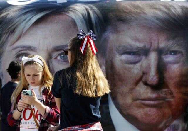 Girls pause near a bus adorned with large photos of candidates Hillary Clinton and Donald Trump before the presidential debate at Hofstra University in Hempstead, N.Y., Monday, Sept. 26, 2016. (AP Photo/Mary Altaffer)