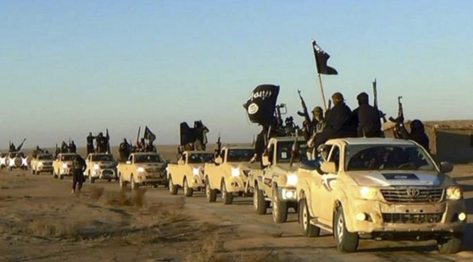 In this undated file photo released by a militant website, which has been verified and is consistent with other AP reporting, militants of the Islamic State group hold up their weapons and wave flags on their vehicles in a convoy on a road leading to Iraq, while riding in Raqqa, Syria. (AP)