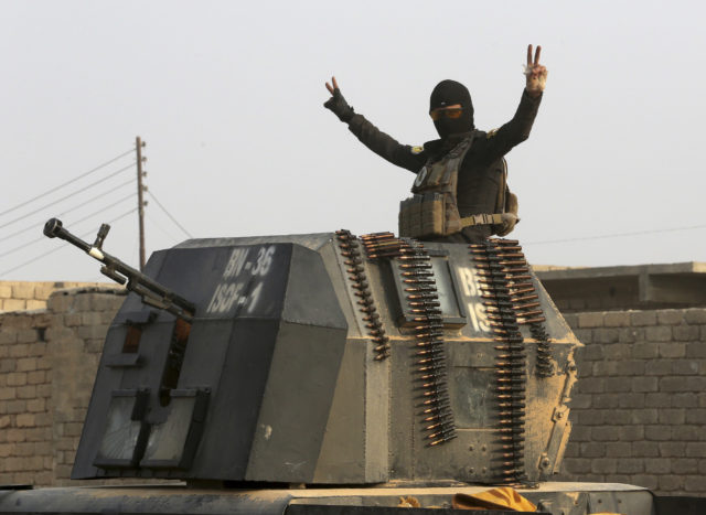 A member of Iraq's elite counterterrorism forces in a military convoy flashes a victory sign as forces advance toward Islamic State positions in the village of Tob Zawa, about 9 kilometers from Mosul, Iraq, Oct. 25, 2016. (AP) 