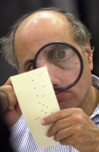 In this Nov. 24, 2000  photo, Broward County, Fla. canvassing board member Judge Robert Rosenberg uses a magnifying glass to examine a disputed ballot during the Florida recount. (AP) 